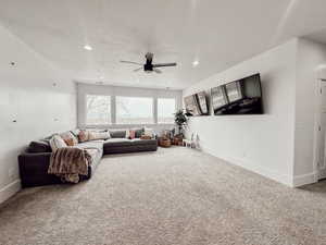 Carpeted living room with a textured ceiling, ceiling fan, and baseboards