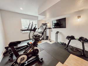 Exercise room with baseboards, a textured ceiling, and wood finished floors