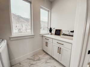 Bar featuring marble finish floor, washer / clothes dryer, baseboards, and a mountain view