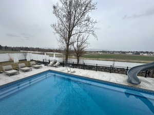 View of swimming pool featuring a fenced backyard, a water slide, a patio, and a fenced in pool
