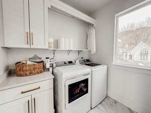 Washroom featuring baseboards, marble finish floor, independent washer and dryer, and cabinet space