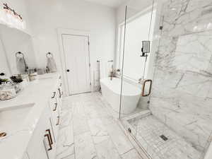 Bathroom featuring a freestanding tub, a sink, a marble finish shower, marble finish floor, and double vanity