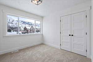 Unfurnished bedroom with a closet, a textured ceiling, baseboards, visible vents, and carpet