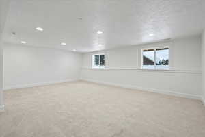 Basement featuring carpet, a textured ceiling, baseboards, visible vents, and recessed lighting