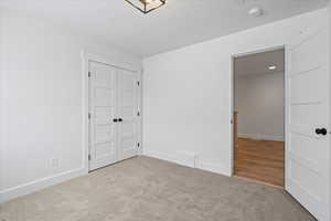 Unfurnished bedroom with baseboards, a closet, carpet floors, and a textured ceiling