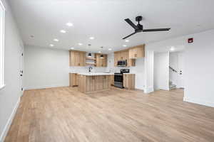 Kitchen with light countertops, light wood finished floors, ceiling fan, stainless steel appliances, and light brown cabinetry