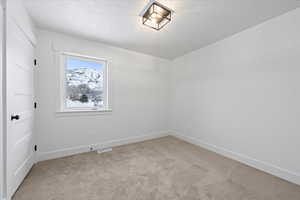 Unfurnished room with baseboards, a textured ceiling, visible vents, and light colored carpet