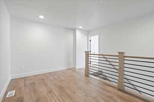 Empty room featuring baseboards, visible vents, recessed lighting, and light wood finished floors