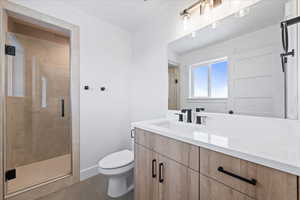 Bathroom featuring baseboards, toilet, tile patterned floors, vanity, and a stall shower
