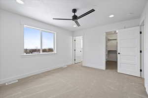 Unfurnished bedroom with visible vents, baseboards, recessed lighting, light carpet, and a walk in closet