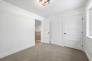 Unfurnished bedroom featuring a closet, carpet, baseboards, and a textured ceiling