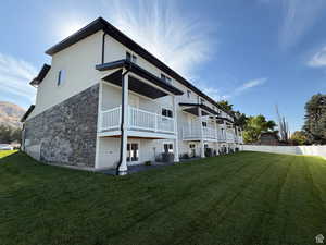 Rear view of house with stone siding, fence, cooling unit, and a lawn