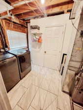 Clothes washing area featuring laundry area, marble finish floor, and separate washer and dryer