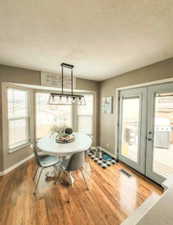Dining area featuring plenty of natural light, a textured ceiling, visible vents, and wood finished floors