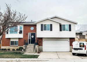 View of front of property featuring an attached garage, brick siding, and concrete driveway