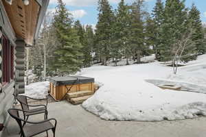 Yard covered in snow with a hot tub and a patio