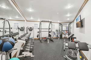 Exercise room with baseboards and crown molding