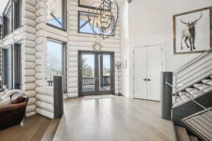 Entryway with stairs, french doors, wood finished floors, and an inviting chandelier