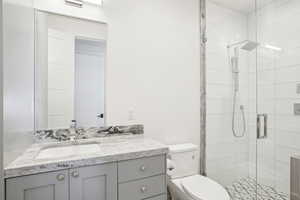 Full bathroom with toilet, a shower stall, and vanity