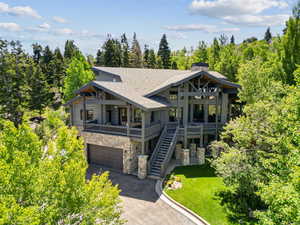 View of front facade featuring stone siding, asphalt driveway, a shingled roof, an attached garage, and a front lawn
