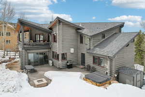 Snow covered house featuring a storage shed, an outdoor fire pit, log siding, roof with shingles, and an outdoor structure