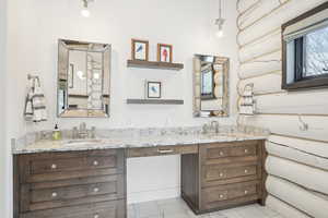 Full bathroom with double vanity, log walls, and a sink