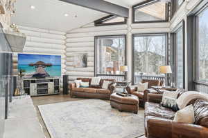 Living room with recessed lighting, rustic walls, wood ceiling, vaulted ceiling with beams, and wood finished floors