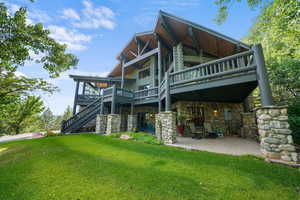 Back of house with a lawn, stone siding, a patio area, stairway, and a wooden deck