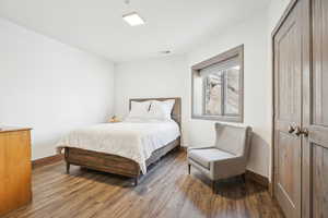 Bedroom featuring baseboards, visible vents, wood finished floors, and a closet