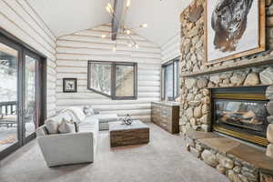 Carpeted living room with a fireplace, high vaulted ceiling, wood ceiling, and a healthy amount of sunlight