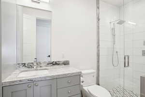 Bathroom featuring a stall shower, toilet, and vanity