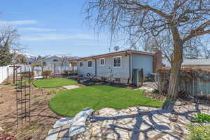 Back of property with a fenced backyard, central air condition unit, a chimney, and a yard
