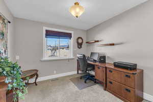 Carpeted home office featuring baseboards and visible vents