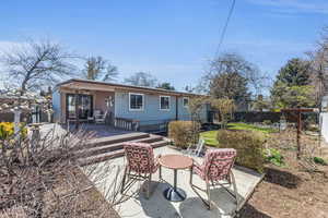 Rear view of house featuring a patio, fence, and a wooden deck