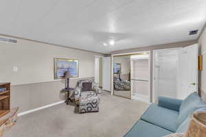 Living area featuring visible vents, carpet, and wainscoting