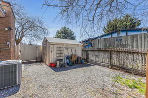 View of yard with central air condition unit, a shed, a fenced backyard, and an outdoor structure