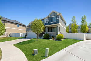 Traditional home featuring concrete driveway, a front lawn, fence, and a porch