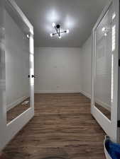 Empty room featuring a textured ceiling, wood finished floors, an inviting chandelier, and baseboards