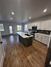 Kitchen with dark wood-style floors, recessed lighting, a sink, white cabinets, and appliances with stainless steel finishes
