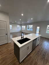 Kitchen featuring an island with sink, dishwasher, a sink, open floor plan, and dark wood-style floors