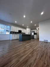 Kitchen with open floor plan, stainless steel refrigerator with ice dispenser, visible vents, and dark wood finished floors