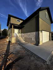 View of front of property with a garage, stucco siding, and board and batten siding