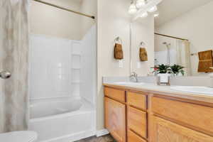 Bathroom with double vanity, shower / bath combination with curtain, tile patterned flooring, and a sink