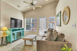 Living area with carpet, lofted ceiling, ceiling fan, and visible vents