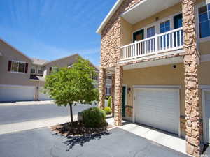 View of front of house with stone siding, stucco siding, and a balcony
