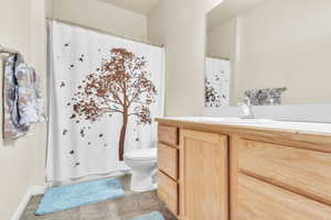 Bathroom featuring curtained shower, toilet, tile patterned flooring, and vanity