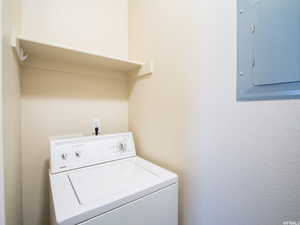 Washroom with electric panel, laundry area, and washer / dryer