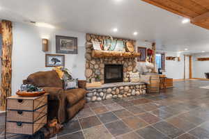Rustic downstairs recreation room with stone fireplace and slate floors