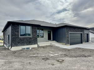 Prairie-style home featuring a garage, a shingled roof, stone siding, and concrete driveway