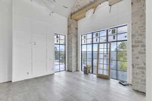 Unfurnished room featuring light wood-type flooring, a high ceiling, and a decorative wall